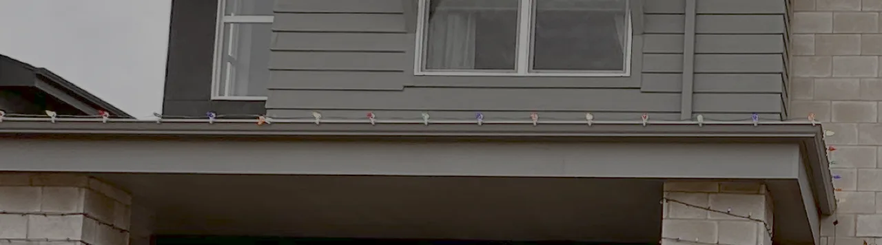 C9 Christmas light bulbs and clips visible along a roofline in daylight