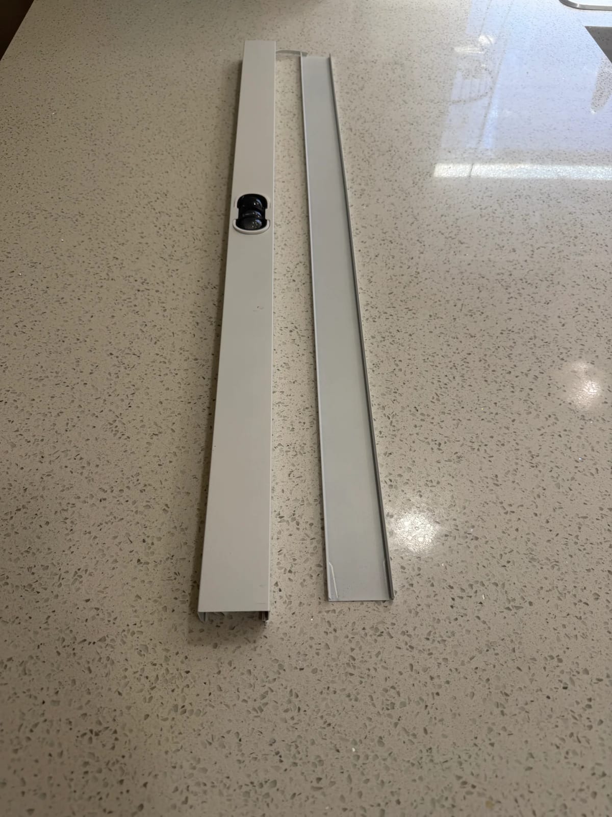 The two parts of the aluminum channel system shown side by side: the base channel with a bulb seated inside, and the snap-on cap that conceals the wiring.