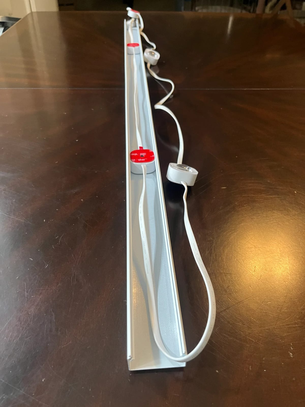 End-on view down a length of installed aluminum channel showing multiple bulbs seated in the channel with their wiring routed through the interior cavity.