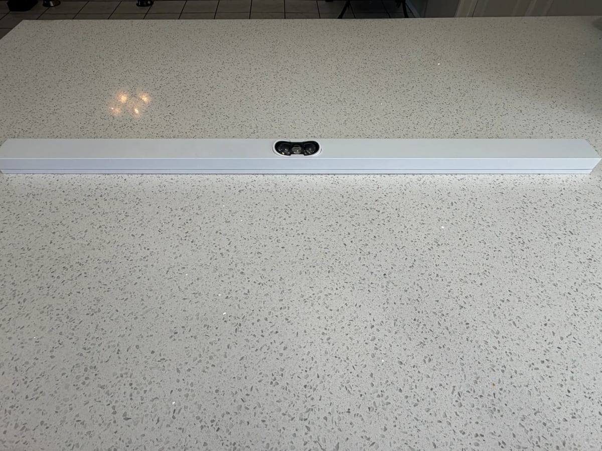 A length of white aluminum permanent lights channel laid on a clean countertop, showing the recessed bulb opening and clean factory finish.