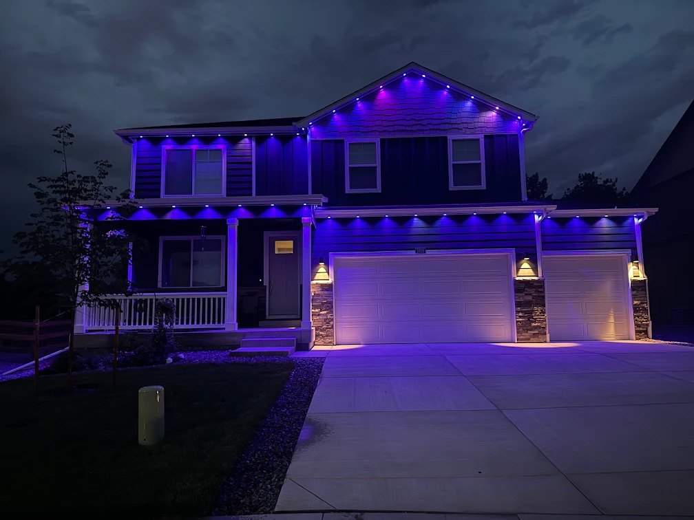 Two-story Denver metro home at night with purple permanent lights installed by 5280 Lights along the gables, porch, and garage rooflines