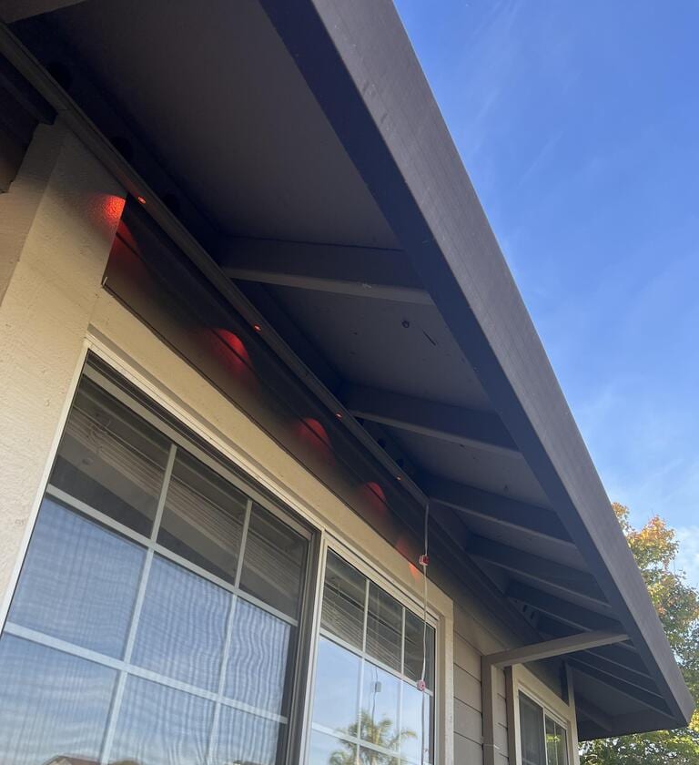 Daylight close-up of an installed channel along a home's fascia, with bulbs gently glowing warm white during the day, demonstrating the clean architectural finish.