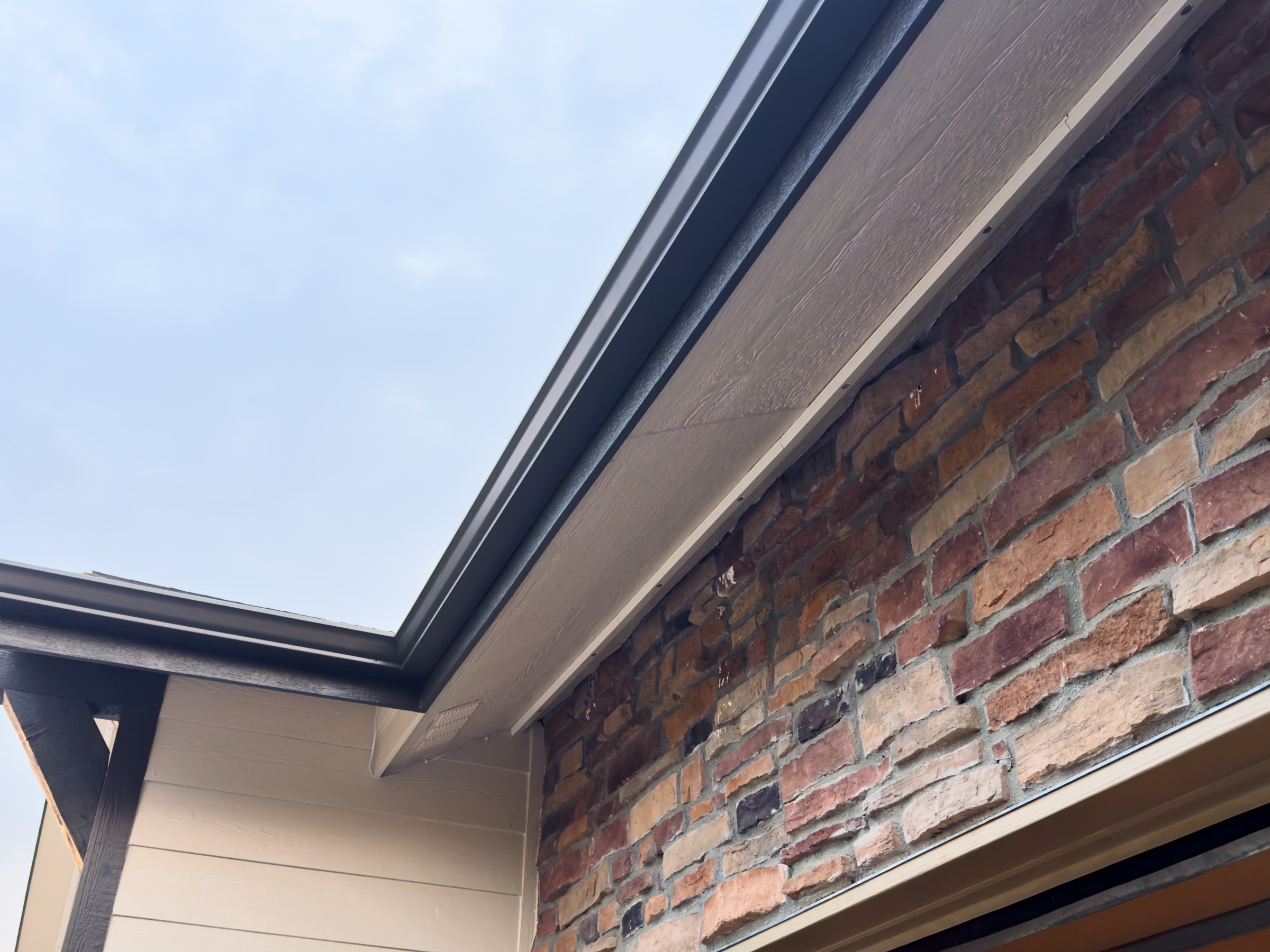 Powder-coated aluminum SnapTrack channel screwed into the soffit of a Parker CO home in daylight, wiring fully concealed