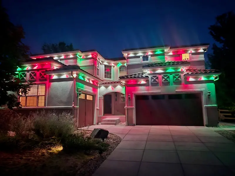 Two-story stucco home in Denver Metro at night with Govee Prism permanent lights in SnapTrack glowing red, green, and white along every roofline and gable