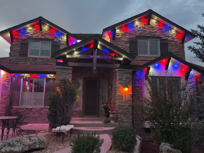 Front entry and gables of a stone-and-stucco Denver Metro home at night with Govee Pro permanent lights in red, white, and blue