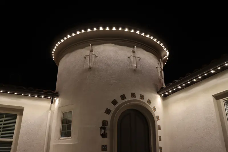 Close-up of 5280 Signature permanent lighting in warm white around a curved turret, showing the tight bulb spacing