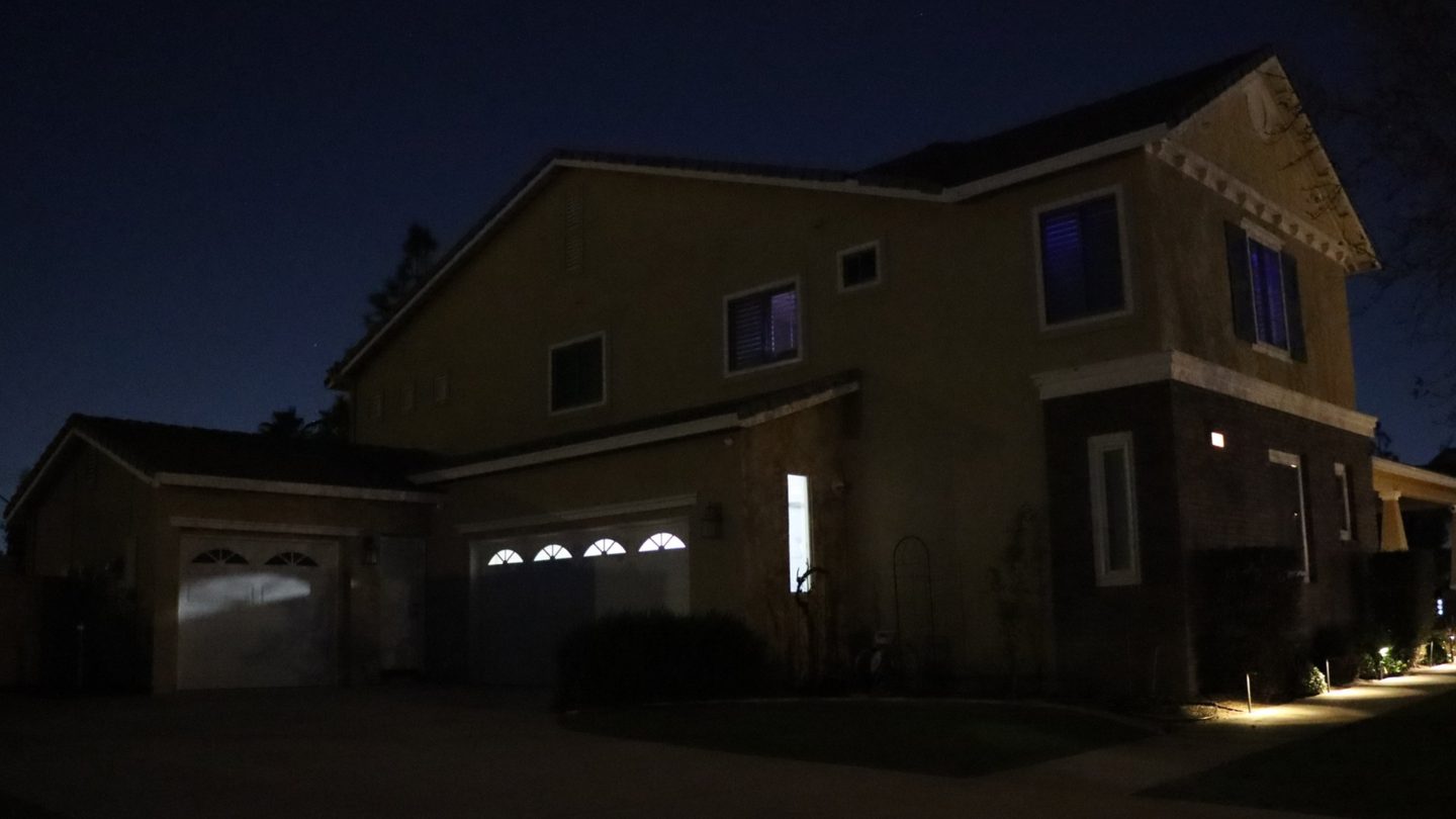 The same two-story home at night before permanent lighting, with a dark roofline